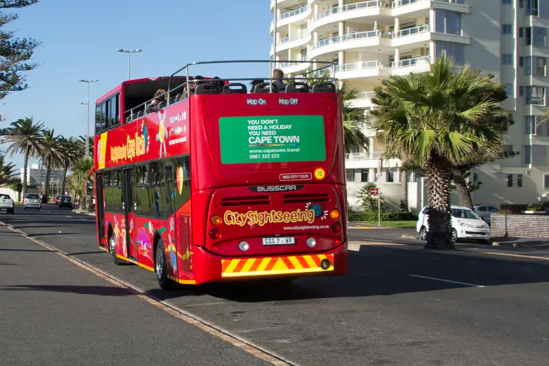 A City Sightseeing red bus on the Cape Town seafront.